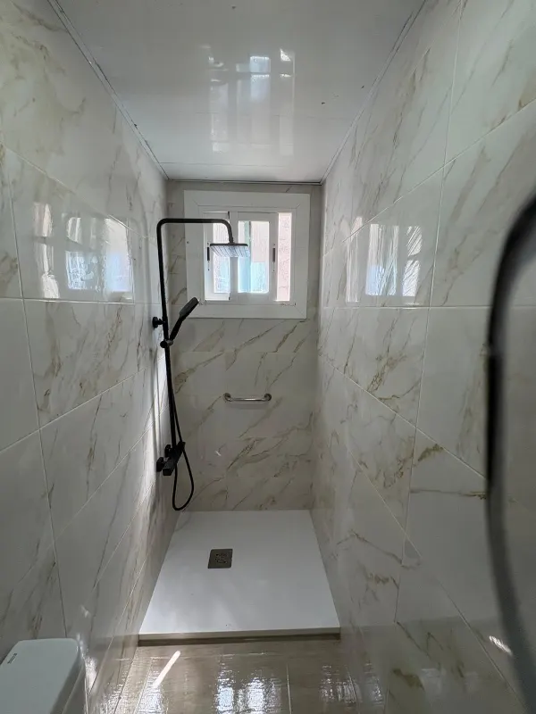 Detalle de ducha y mampara en baño de mármol reformado - Barcelona