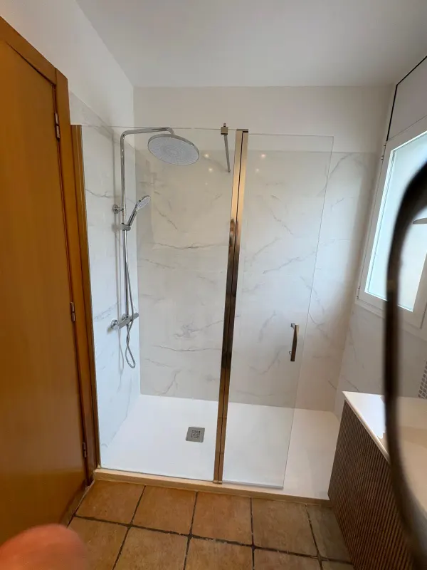 Baño reformado con suelo terracota conservado y mampara de cristal